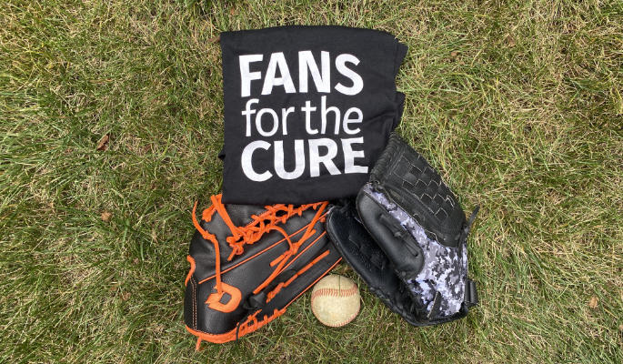 Two baseball gloves, a baseball, and a Fans for the Cure t-shirt