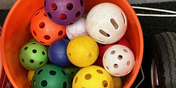 A bucket of different colored Wiffle balls