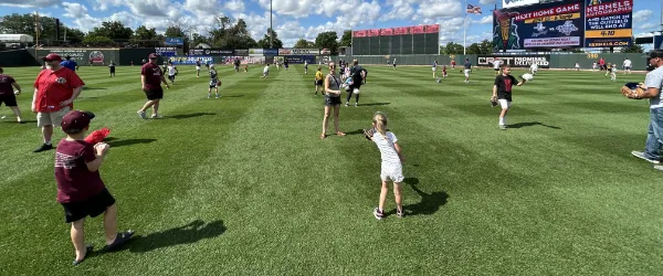 Families playing catch in the outfield of the Cedar Rapids Kernals