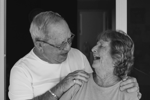 An older man and woman looking at each other warmly and laughing