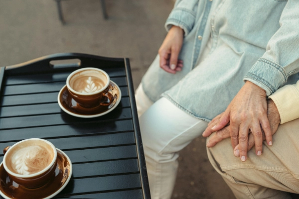 An older couple drinking coffee and holding hands