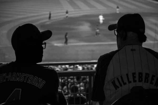 Two men watch a baseball game from the stands
