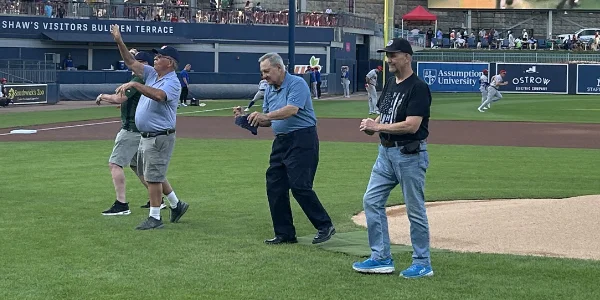 Rico Petricelli and others from Fans for the Cure throw a pitch at Polar Park